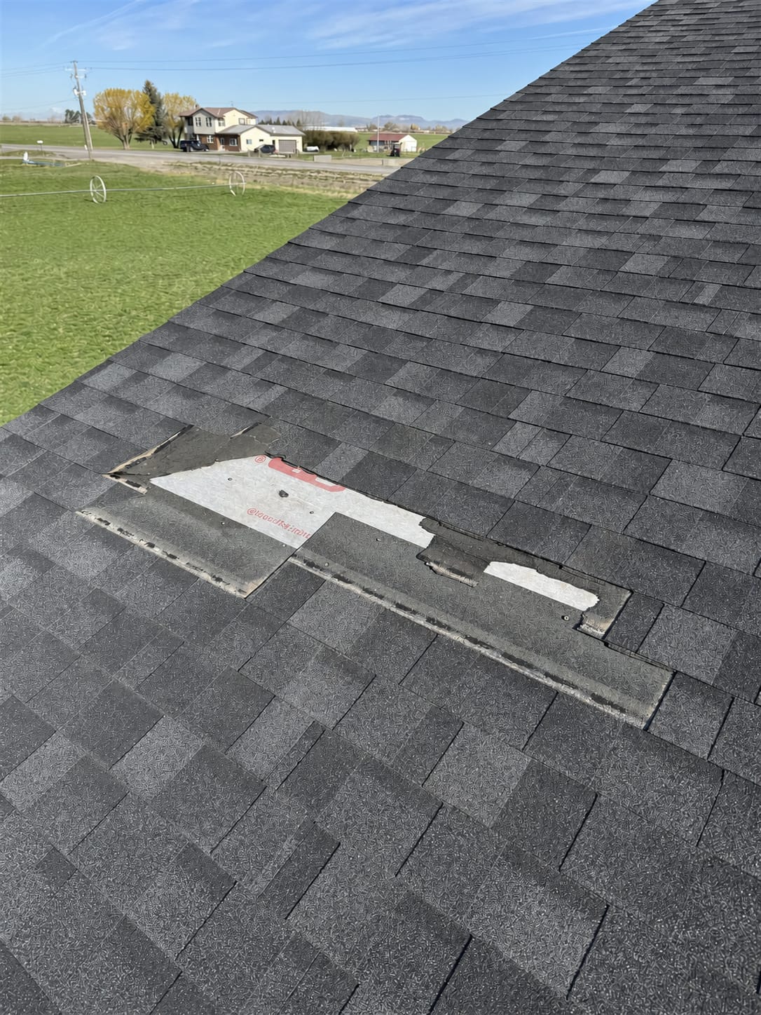 Asphalt roof with a section of shingles torn away, exposing the underlayment