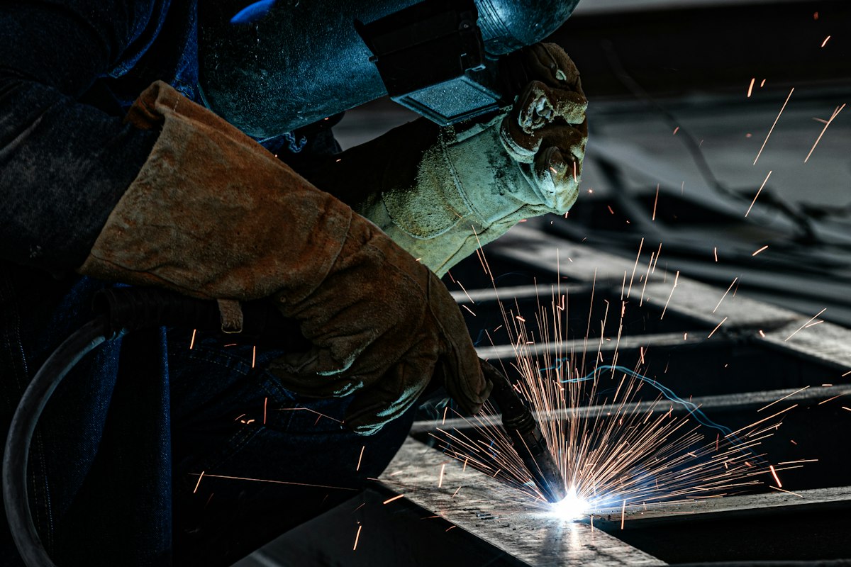 Metalworker welding a custom steel piece with sparks flying