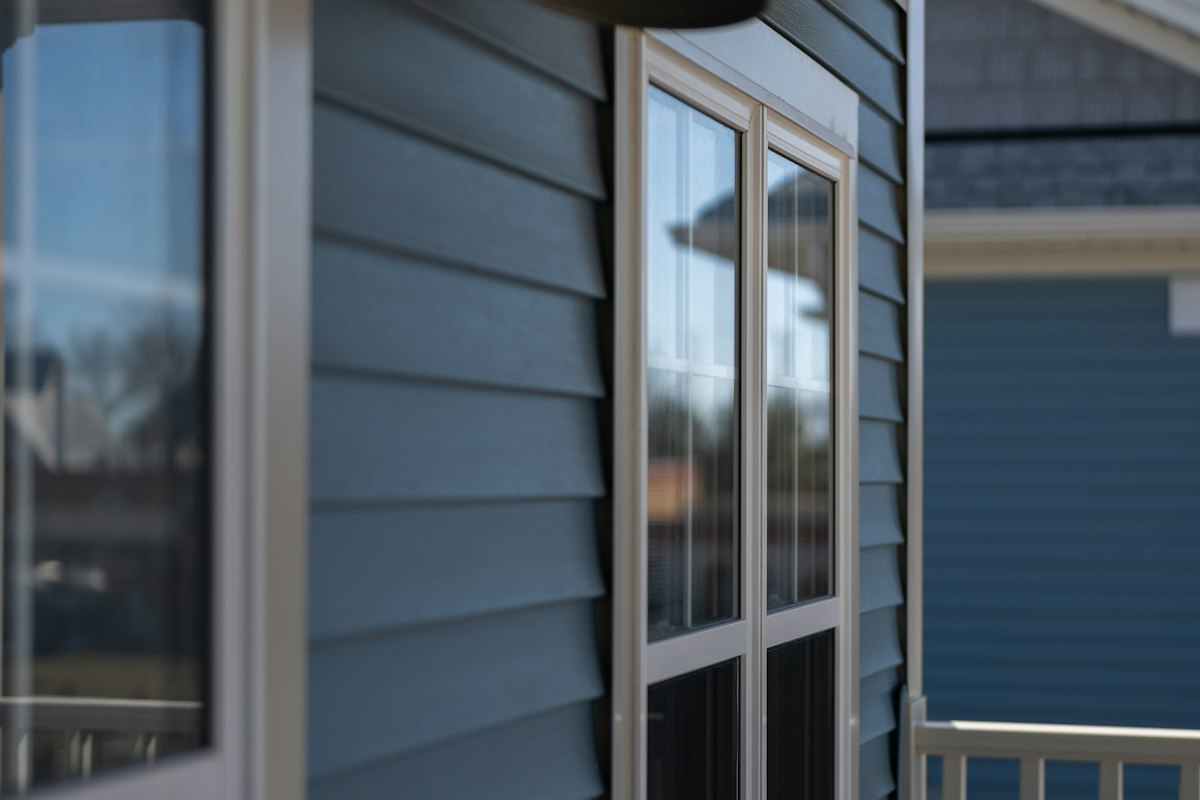 Blue lap siding with white trim around a window on a home